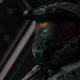 The Master Chief, with his helmet on, looks to the camera.